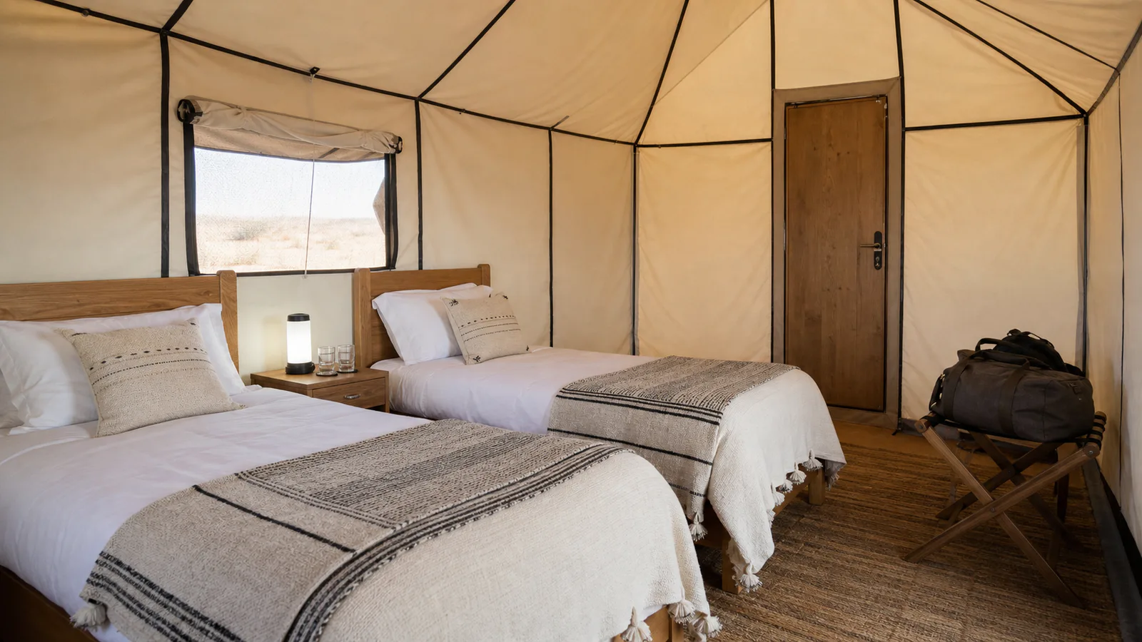 Twin beds, ventilation, lighting and luggage storage inside a practical desert camp tent