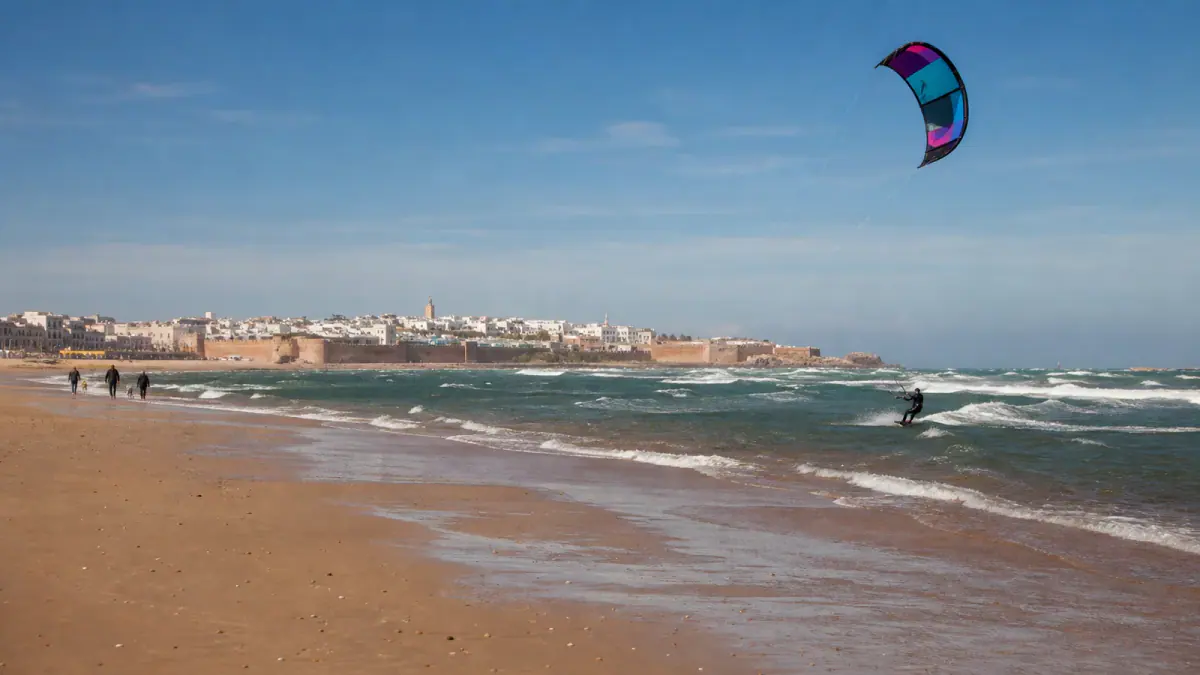 Kitesurfer riding the wind on Essaouira beach with the medina in the distance