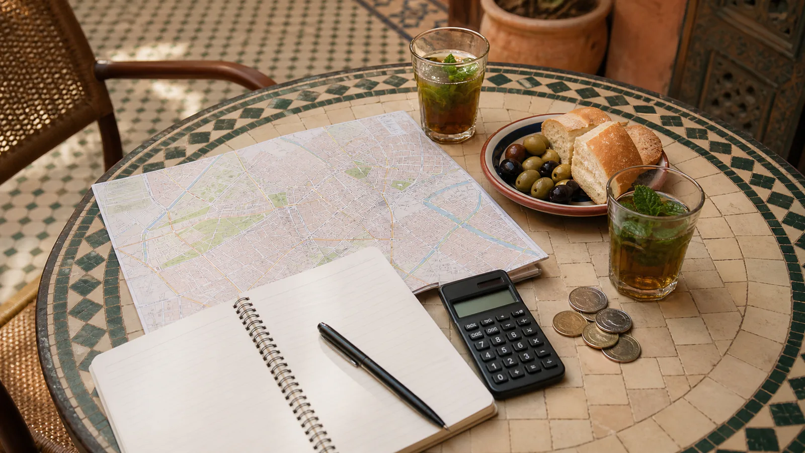 Mint tea, a map and notebook used to plan a Marrakech daily budget