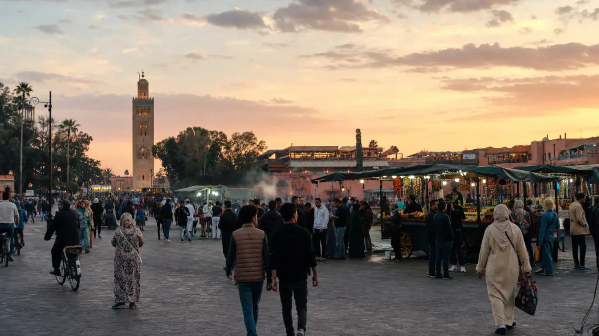 People gathering around food stalls in Jemaa el-Fna at sunset in Marrakech