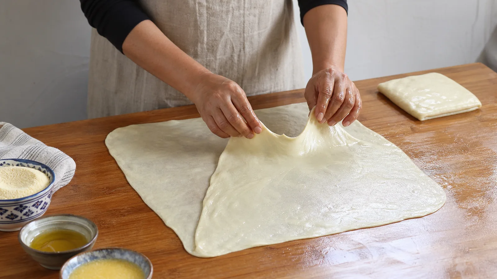 Cook stretching thin msemen dough and folding the first side toward the center